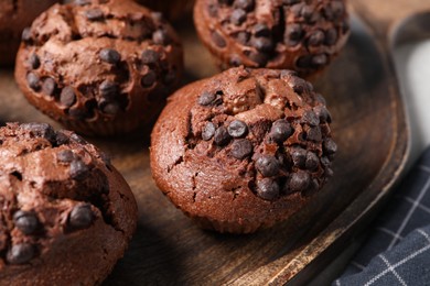 Photo of Tasty chocolate muffins on wooden serving board, closeup