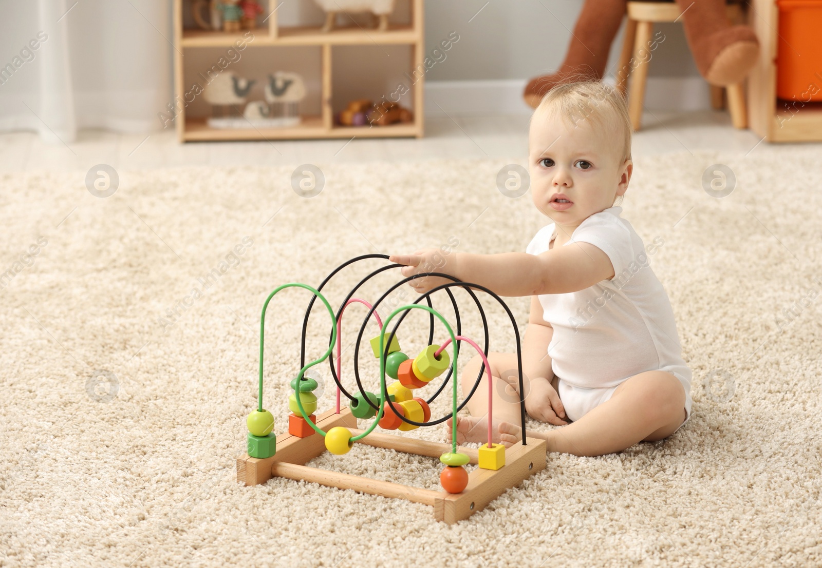 Photo of Children toys. Cute little boy playing with bead maze on rug at home