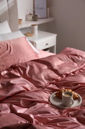 Breakfast tray on bed with beautiful pink silk linens indoors