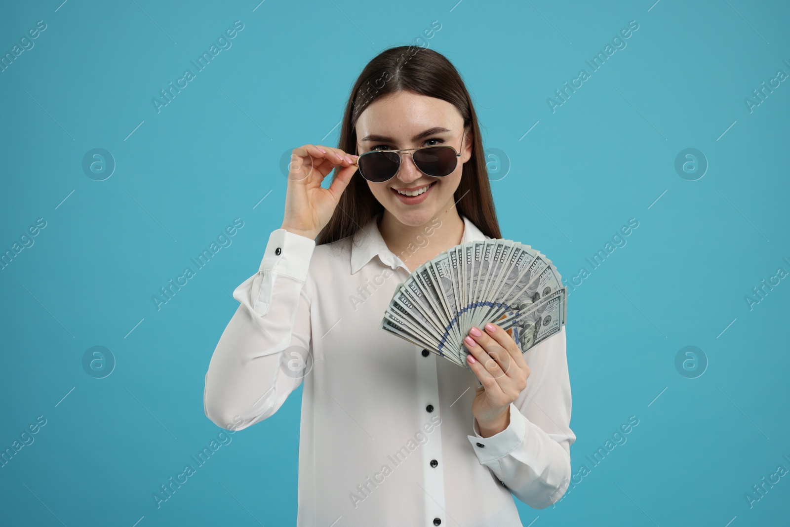 Photo of Happy woman with dollar banknotes on light blue background