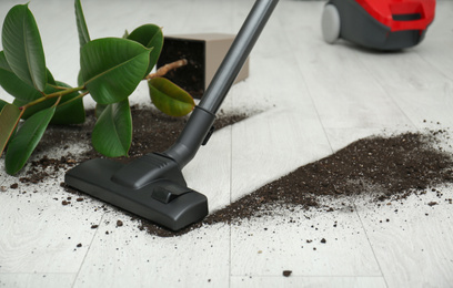 Photo of Removing soil from wooden floor with vacuum cleaner at home