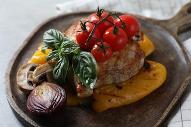 Serving board with tasty grilled meat and vegetables on light table, closeup