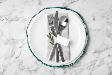 Beautiful table setting with cutlery, napkin and plate on marble background, top view