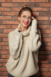 Photo of Beautiful young woman in warm sweater near brick wall