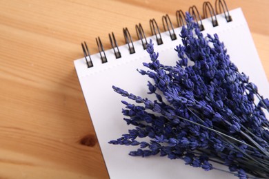 Bouquet of beautiful preserved lavender flowers and notebook on wooden table, top view. Space for text
