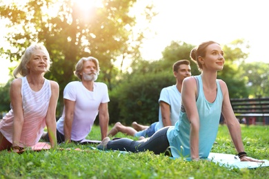 Photo of Group of people practicing morning yoga in park