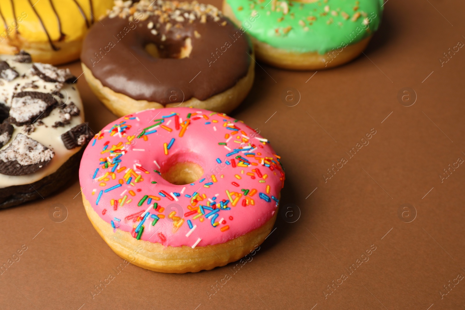 Photo of Sweet tasty glazed donuts on brown background, closeup. Space for text