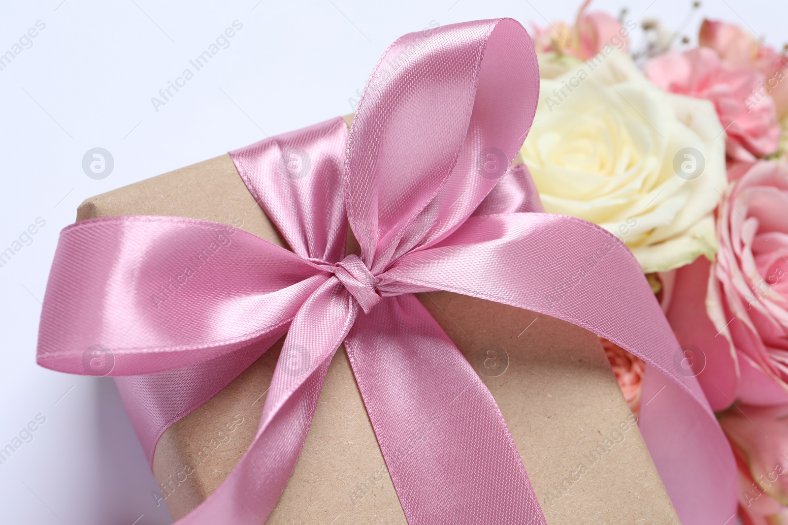 Photo of Gift box and beautiful flowers on white background, closeup