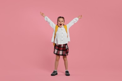 Photo of Emotional schoolgirl with backpack on pink background