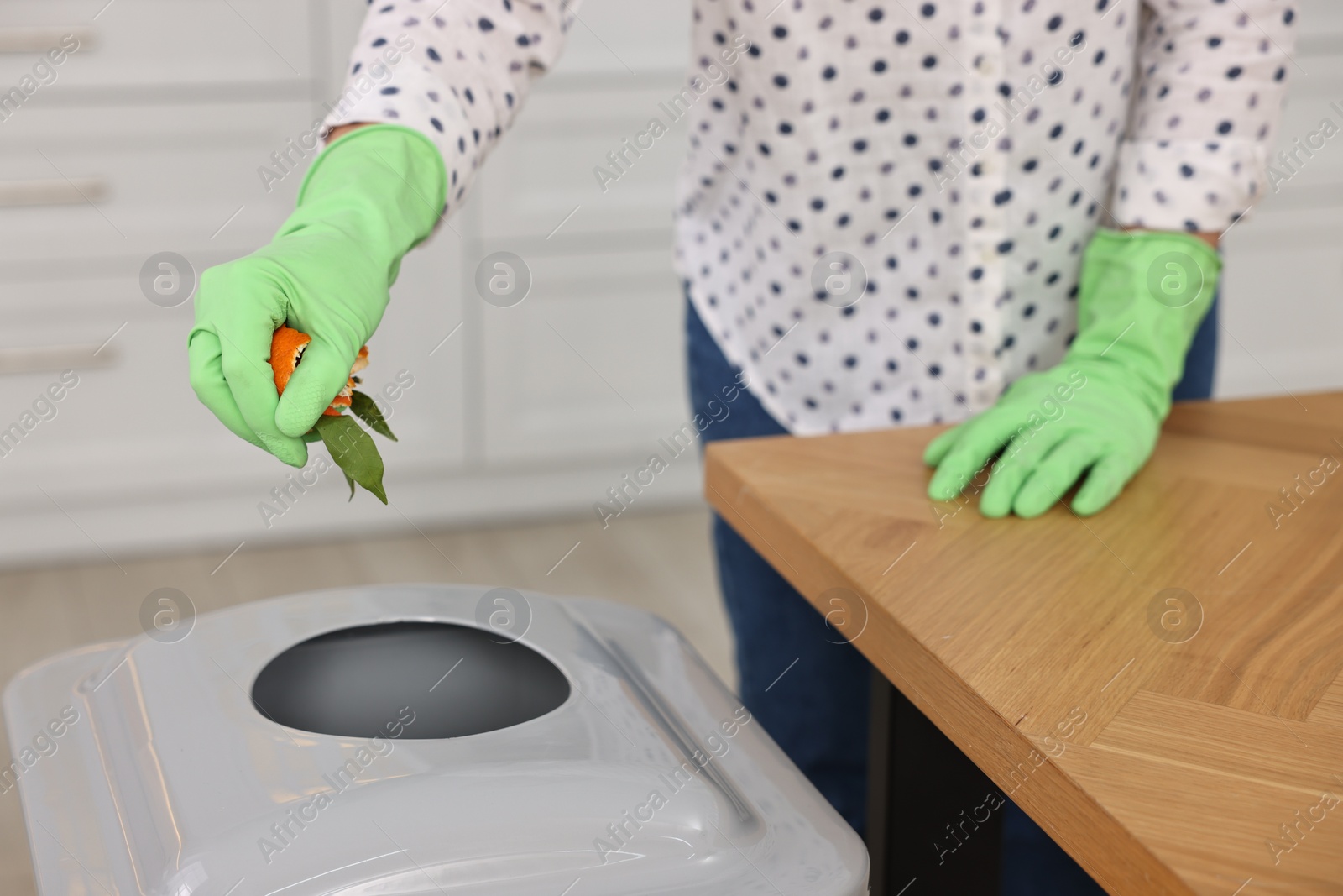 Photo of Woman separating garbage at wooden table indoors, closeup