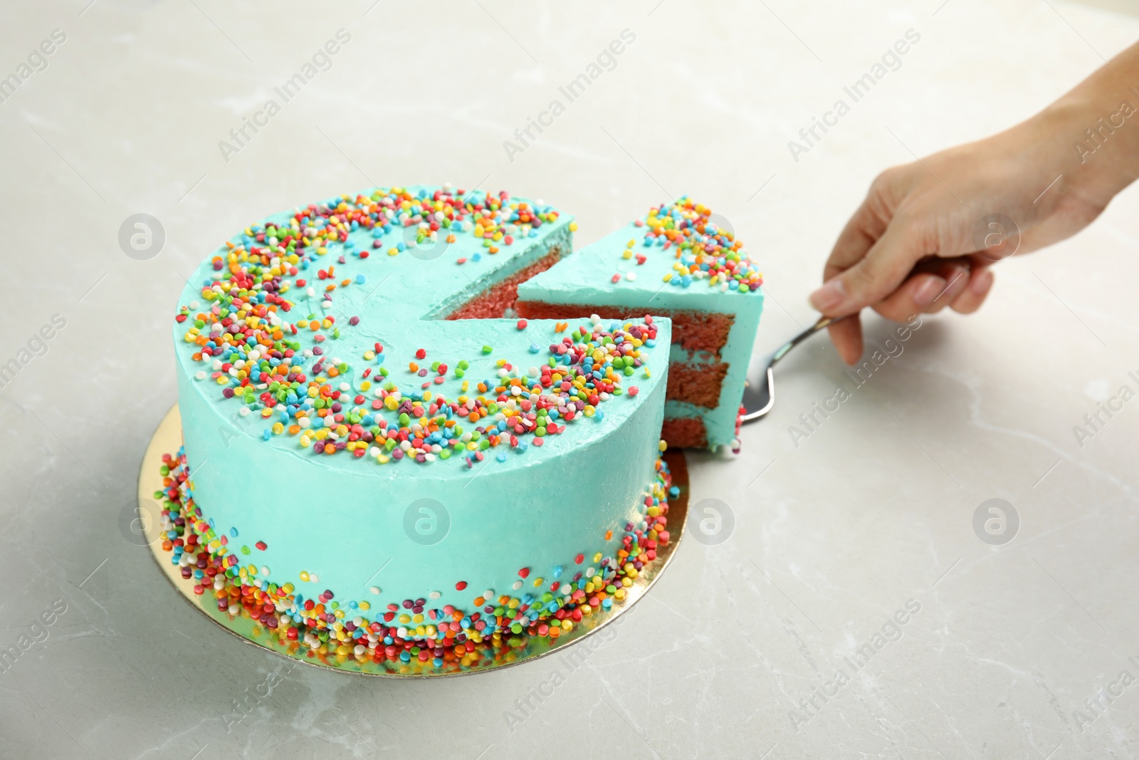 Photo of Woman taking slice of fresh delicious birthday cake at table, closeup