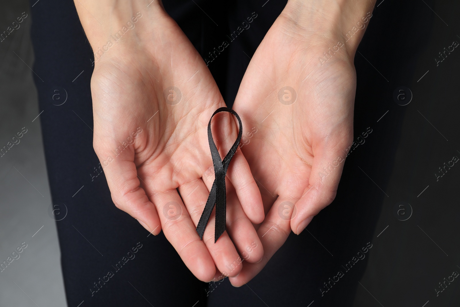 Photo of Young woman holding black ribbon, closeup. Funeral symbol