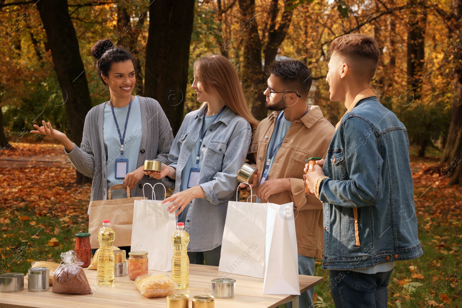 Photo of Group of volunteers packing food products at table in park