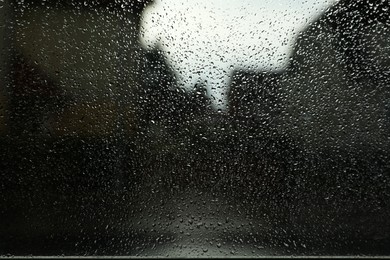 Photo of Blurred view of city street from window on rainy day