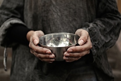 Photo of Poor homeless woman with empty bowl outdoors, closeup