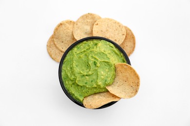 Delicious guacamole made of avocados and nachos on white background, top view