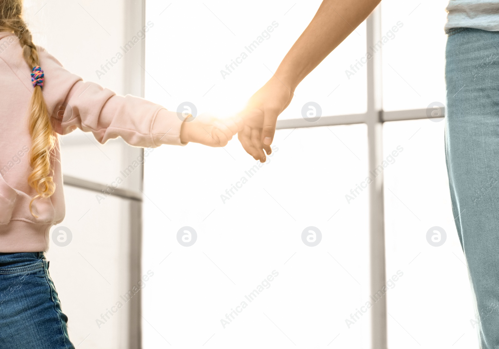 Photo of Mother holding hands with her child indoors, closeup. Happy family