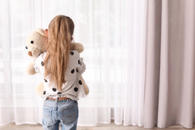 Photo of Lonely little girl with toy indoors. Autism concept