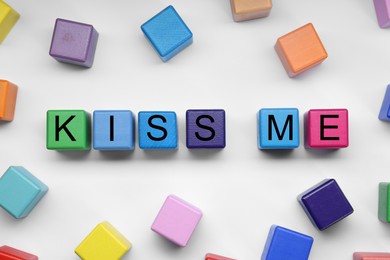 Colorful cubes with phrase Kiss Me on white background, flat lay
