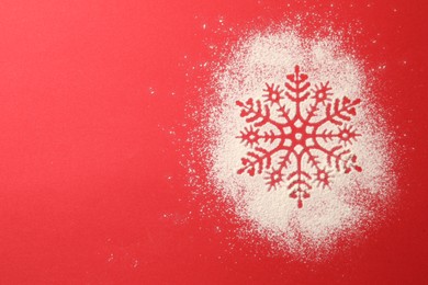 Photo of Snowflake silhouette made with artificial snow on red background, top view. Space for text