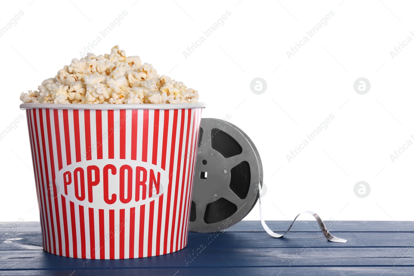 Photo of Delicious popcorn and movie reel on blue wooden table against white background