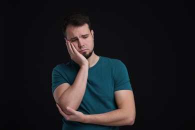 Portrait of sad man on black background