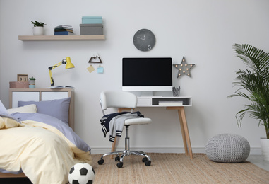 Stylish teenager's room interior with comfortable bed and workplace