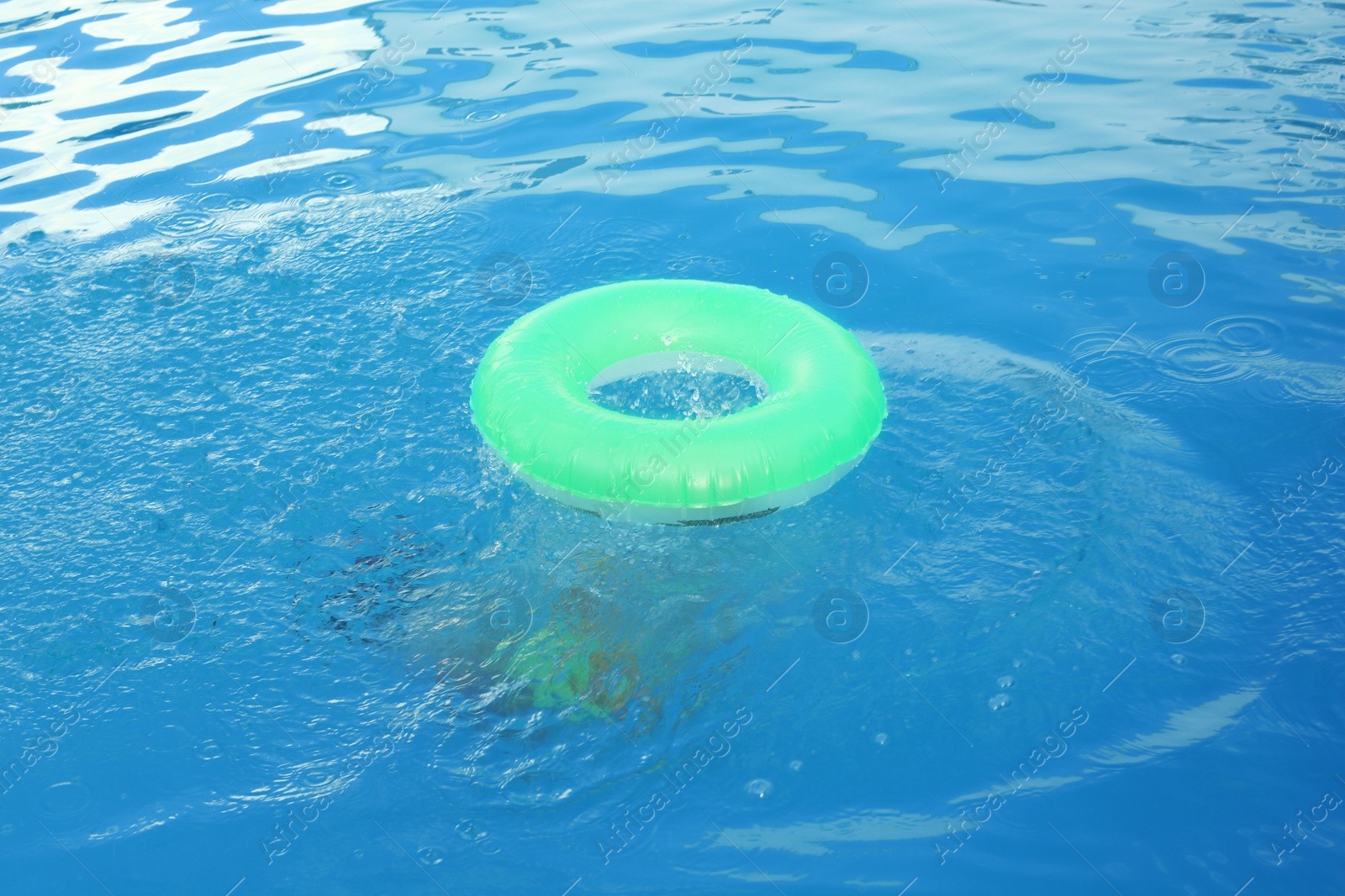 Photo of Little child with inflatable ring in outdoor swimming pool. Dangerous situation