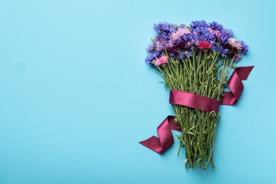 Bouquet of beautiful cornflowers on light blue background, top view. Space for text