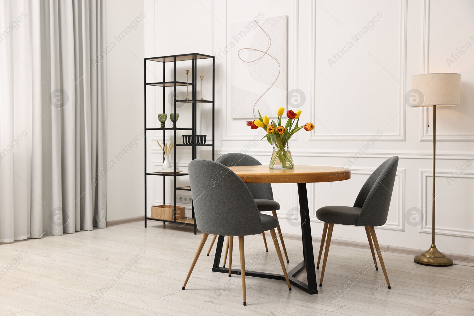 Photo of Stylish dining room interior with comfortable furniture and beautiful tulips