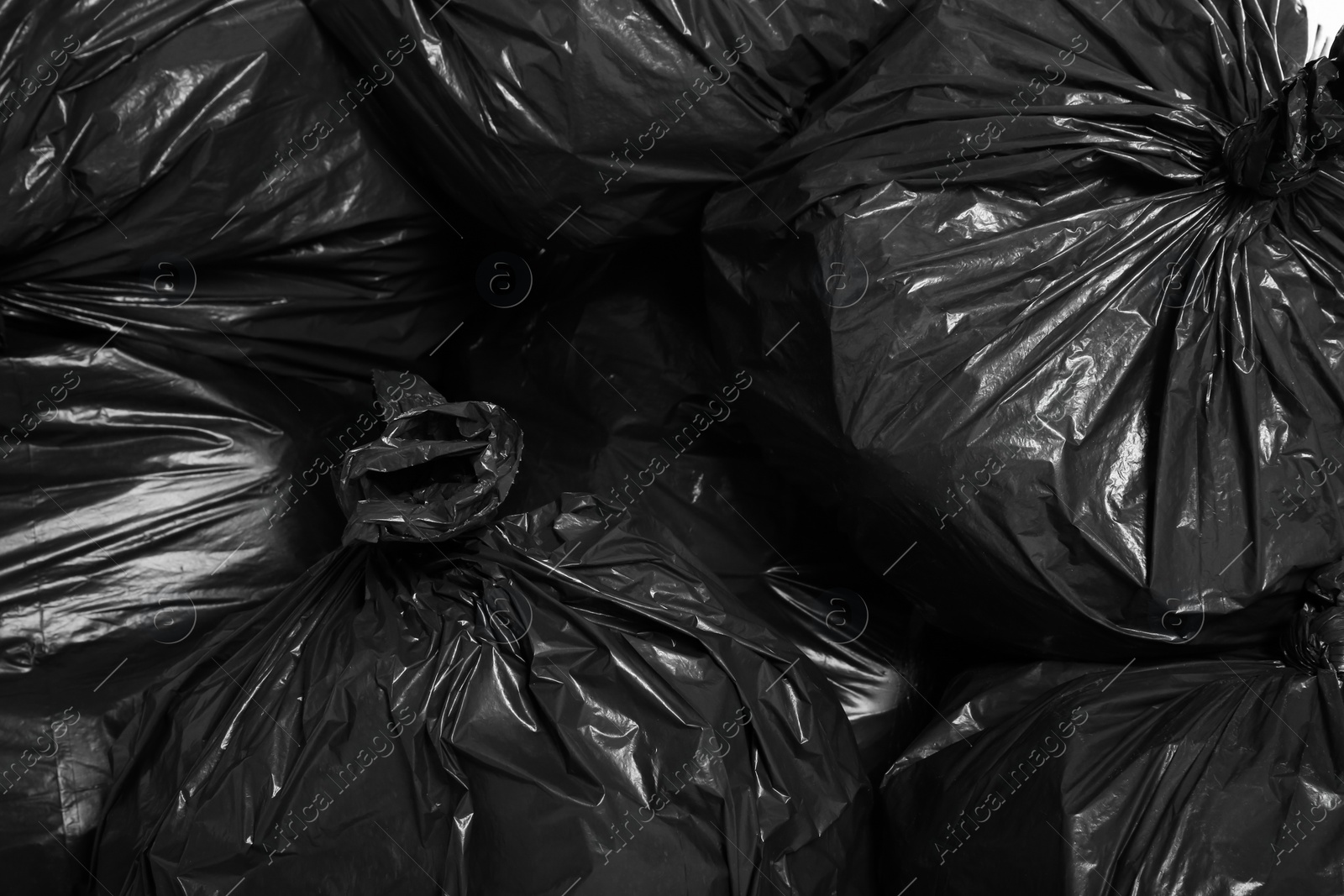 Photo of Black trash bags full of garbage as background, top view