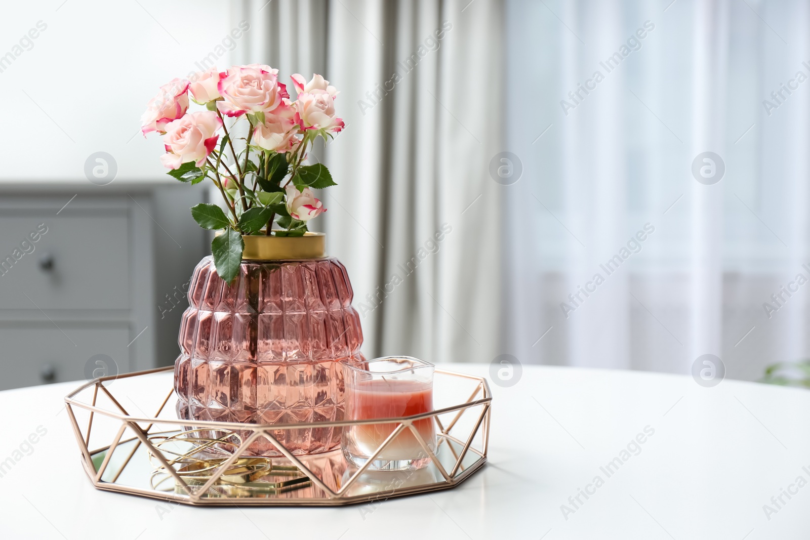 Photo of Vase with beautiful flowers and candle on white table indoors, space for text. Interior elements