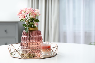 Vase with beautiful flowers and candle on white table indoors, space for text. Interior elements