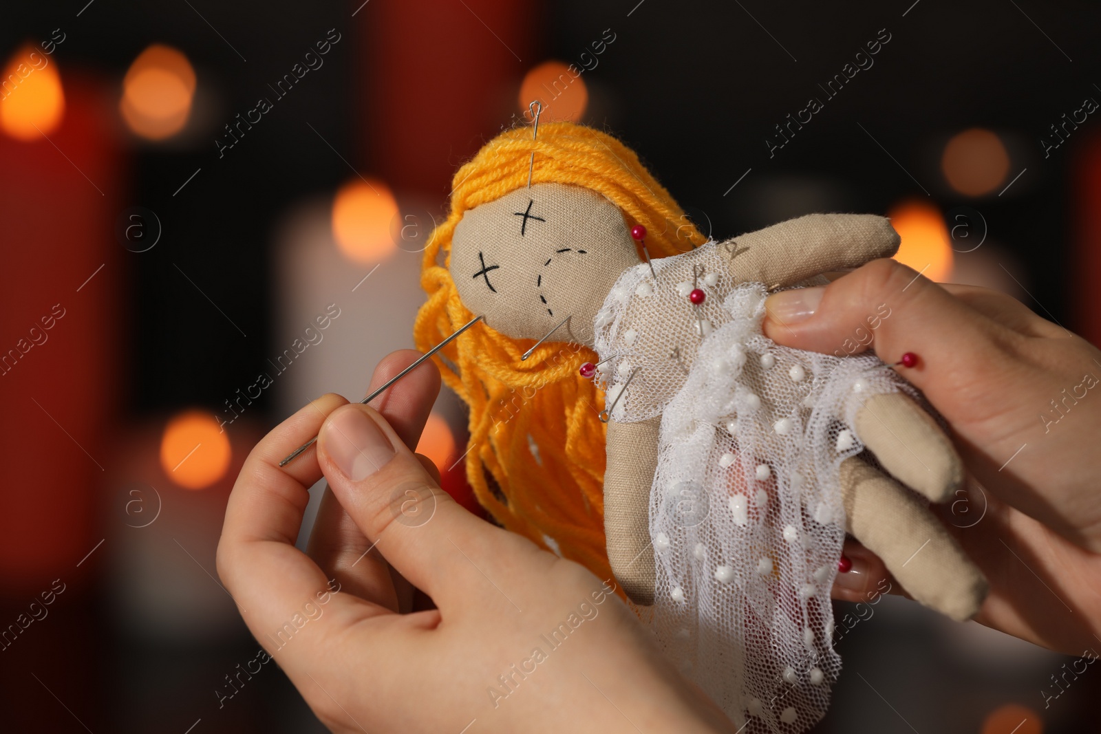 Photo of Woman stabbing voodoo doll with pin in dark room, closeup. Curse ceremony