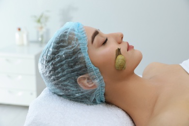 Photo of Young woman receiving snail facial massage in spa salon