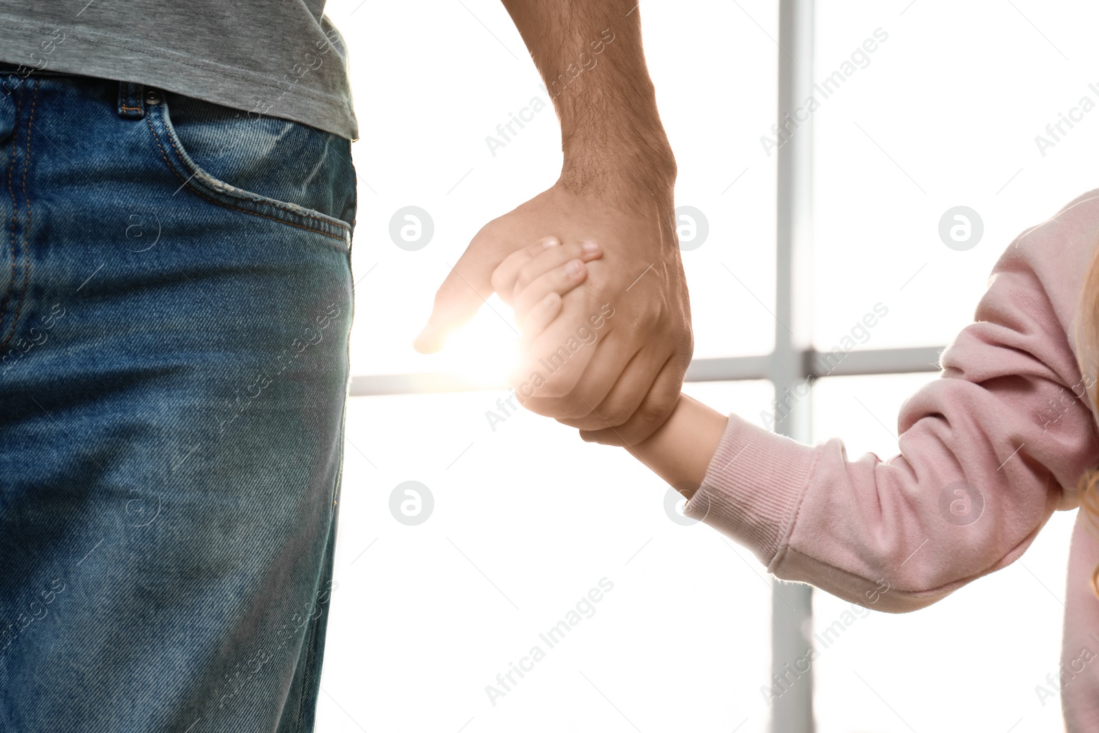 Photo of Father holding hands with his child indoors, closeup. Happy family