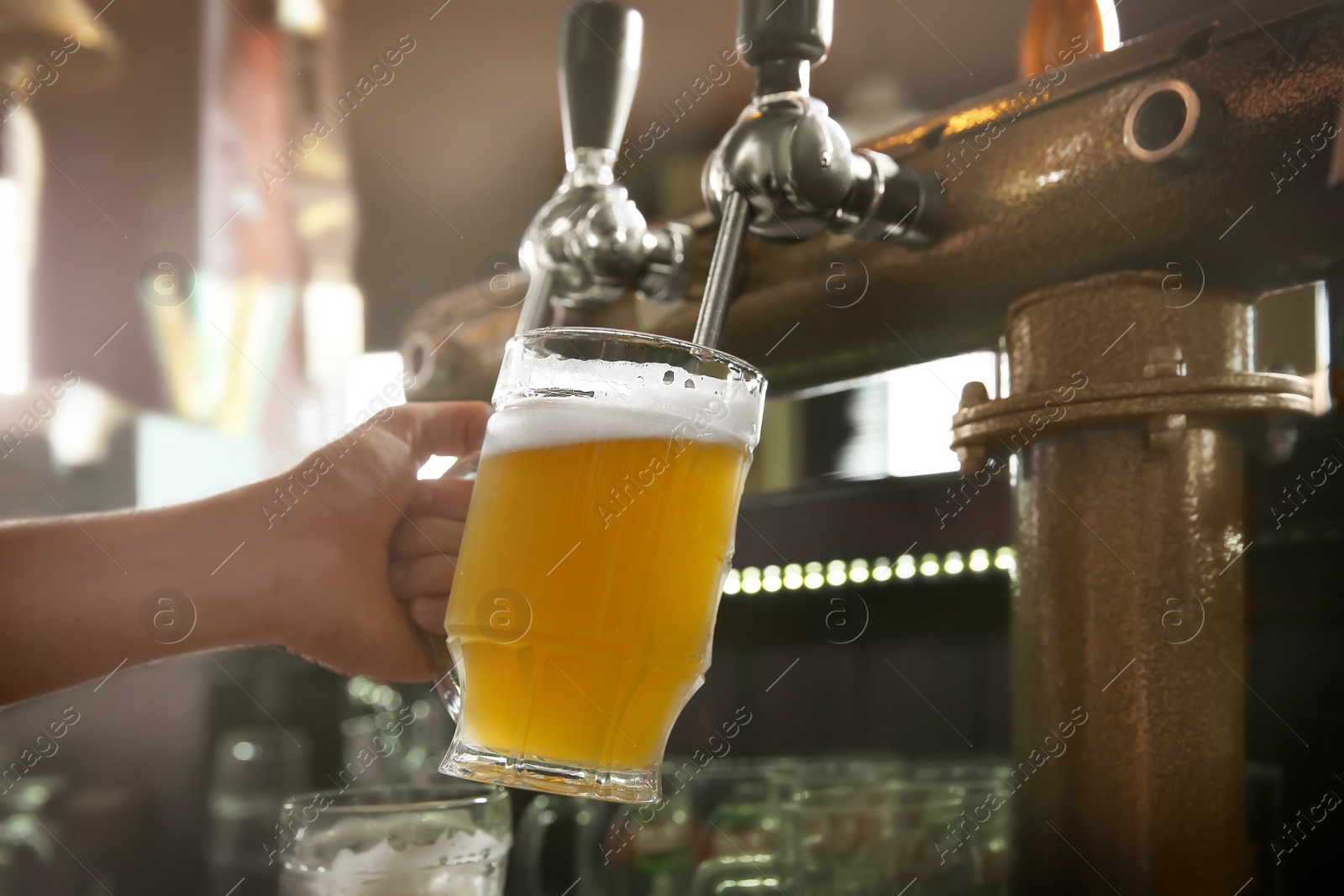 Photo of Bartender pouring beer from tap into glass in bar, closeup