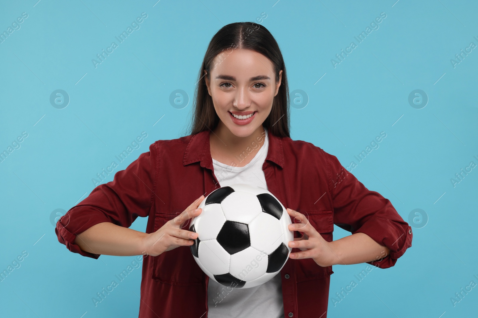 Photo of Happy fan holding soccer ball on light blue background