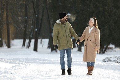 Photo of Happy young couple walking in snowy park on winter day