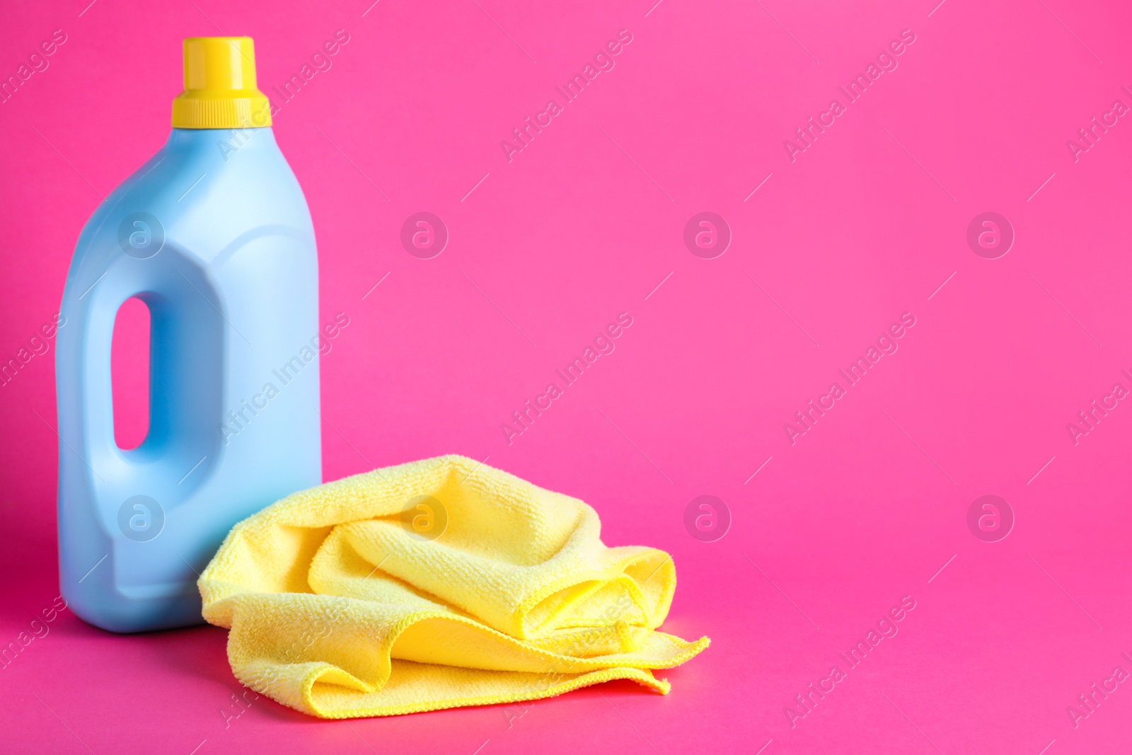 Photo of Microfiber cloth and bottle of detergent on pink background, space for text