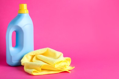 Photo of Microfiber cloth and bottle of detergent on pink background, space for text