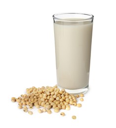 Glass of fresh soy milk and beans on white background