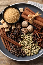 Photo of Plate with different aromatic spices on wooden table, top view