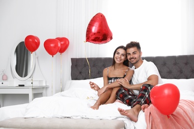 Young couple in bedroom decorated with air balloons. Celebration of Saint Valentine's Day