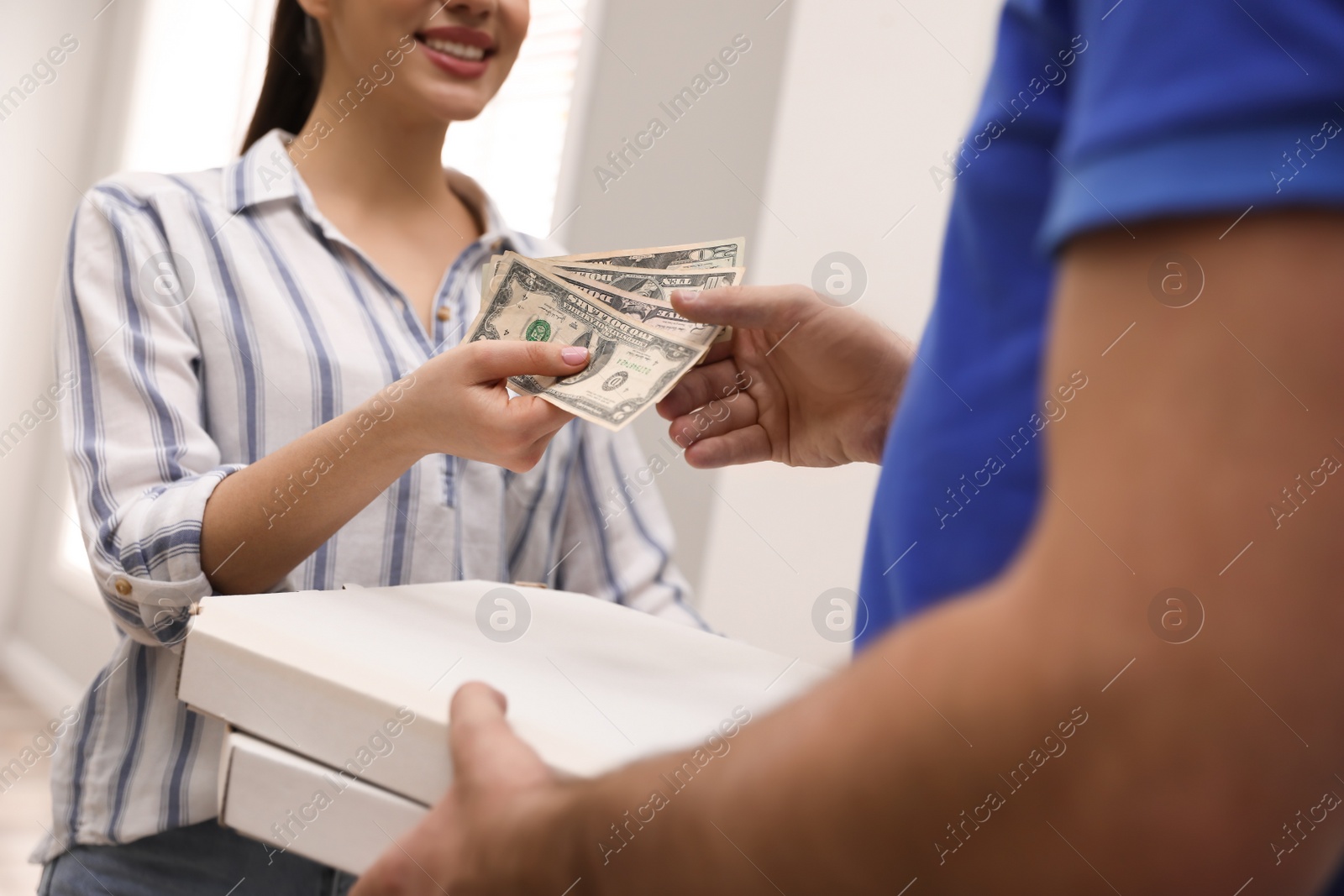 Photo of Woman giving tips to deliveryman indoors, closeup
