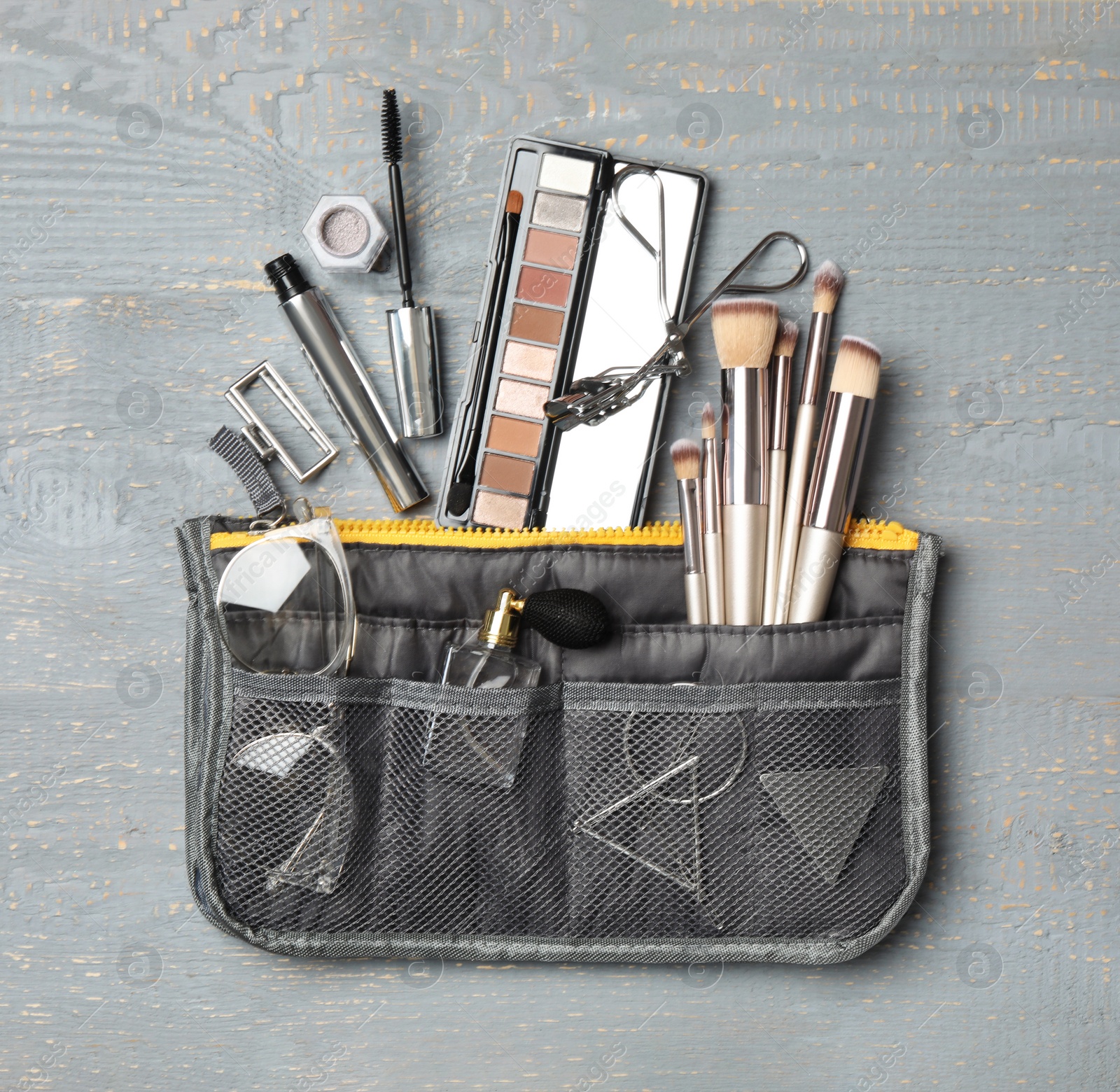 Photo of Cosmetic bag with makeup products and beauty accessories on wooden background, flat lay