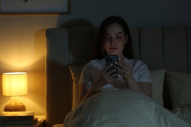 Woman using smartphone in bed at night. Internet addiction