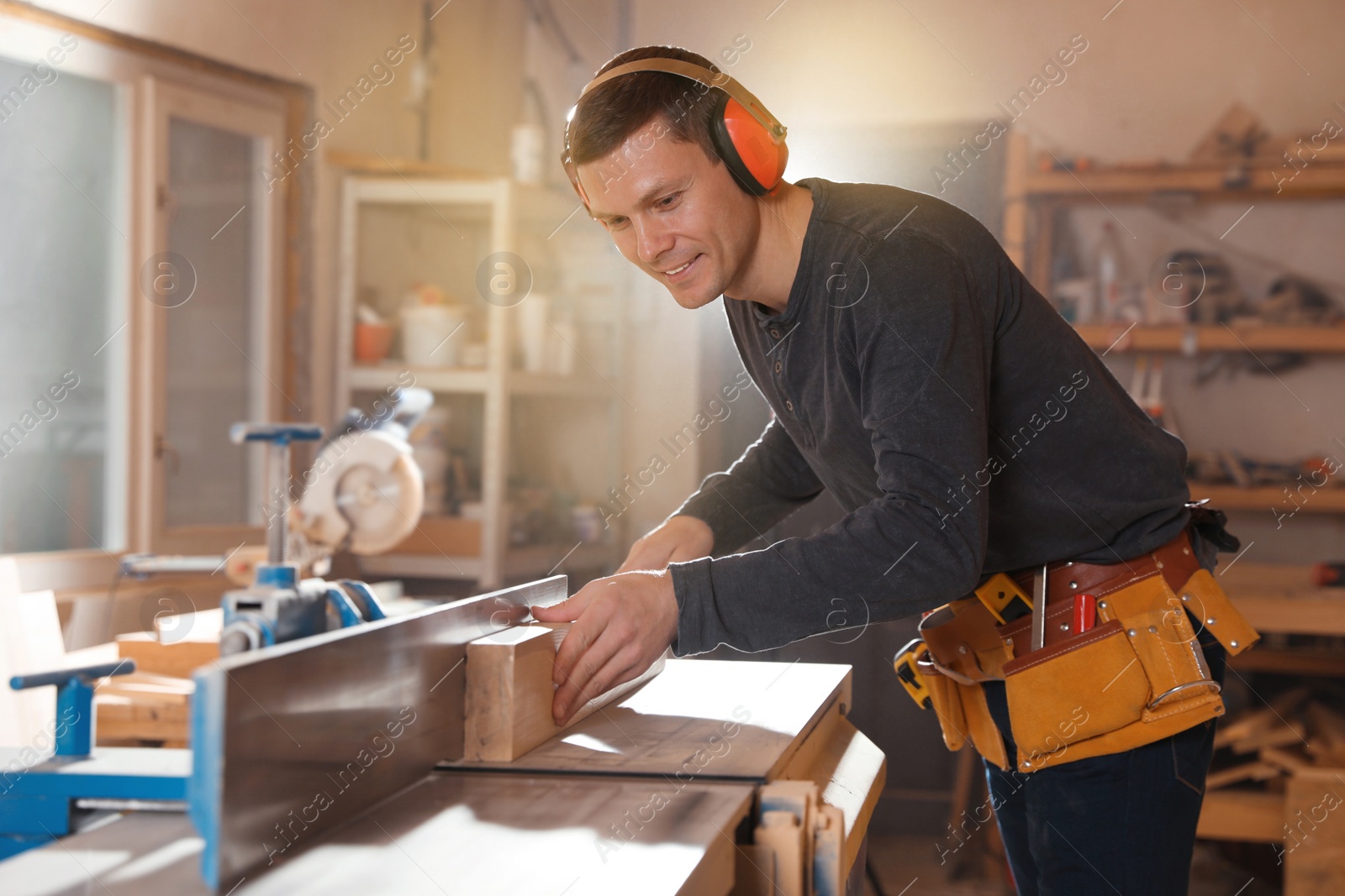 Photo of Professional carpenter working with surface planer in workshop