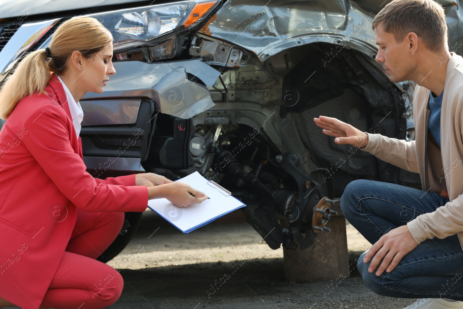 Photo of Man reporting and insurance agent filling claim form near broken car outdoors