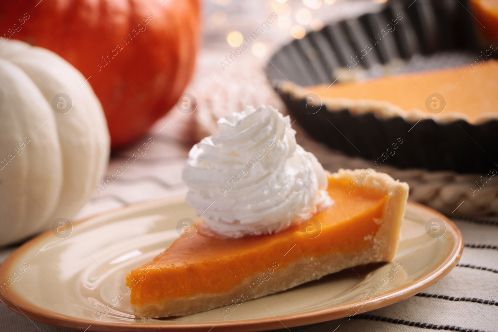 Photo of Piece of fresh homemade pumpkin pie with whipped cream on table